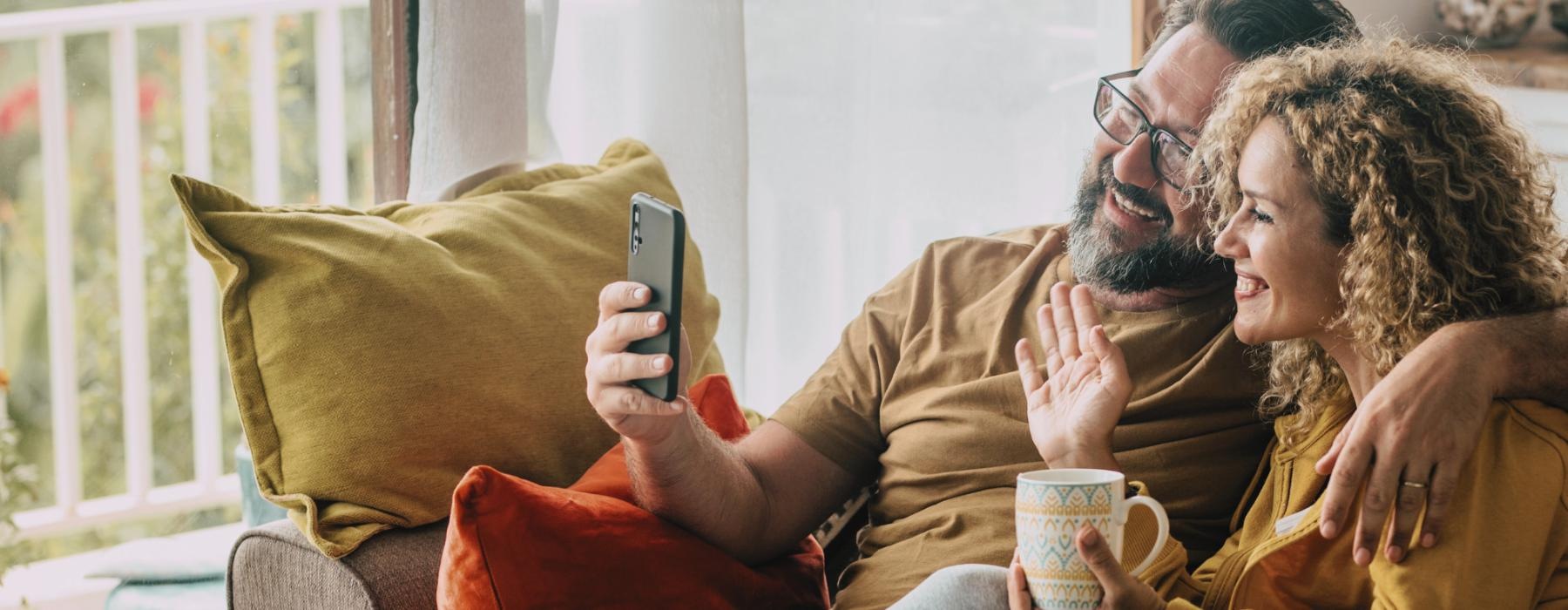 Lifestyle photo of a man and woman sitting on a couch FaceTiming